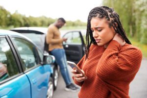 A woman making a call on her cell phone after an auto accident.