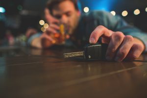Man drinking in a bar while reaching for car keys
