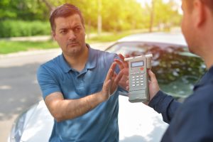 A man refusing to take a breathalyzer test from a police officer.