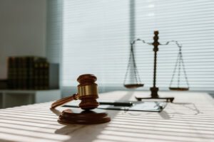 A gavel and plate on a desk, with a set of scales in behind.