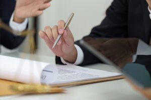 A closeup of a lawyer’s hands, with a pen in one hand and documents in the other.