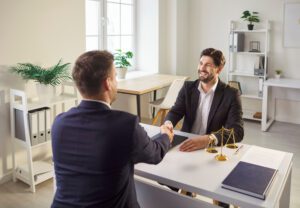 Lawyer and client shake hands after a successful legal consultation in a bright office setting.