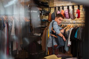 Young man caught shoplifting in a clothing store while nervously looking around.