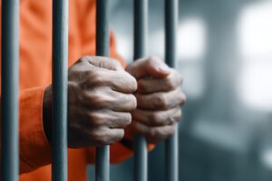 a man inside a jail gripping cell bars