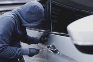 a thief holding a screwdriver opening a car