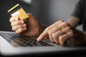 A man holding a credit card while online shopping.